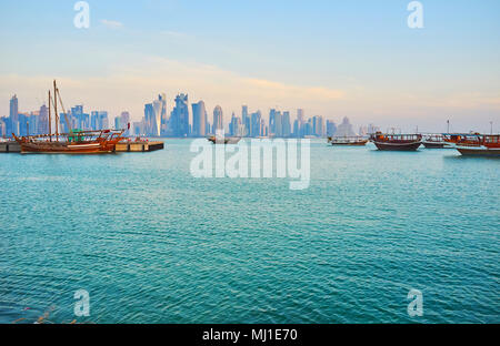 Le port de Doha avec amarré boutre en bois des bateaux et des ondulations sur la surface de l'eau, des gratte-ciels du quartier des affaires sont vus sur le contexte, le qat Banque D'Images