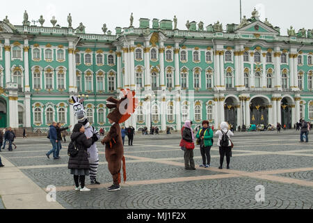 Les touristes marchant sur la place du palais en face de l'Hermitage (Palais d'hiver), Saint-Pétersbourg, Russie. Deux personnes en robes de fantaisie de zebra et cheval . Banque D'Images