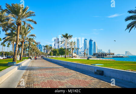 La belle promenade en bord de mer avec des jardins de palmiers et de gazon juteux s'étend le long de la baie Ouest - la zone d'affaires de luxe à Doha, Qatar. Banque D'Images