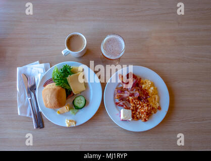 Petit-déjeuner avec deux plaques produites par exemple, du bacon et des œufs brouillés et du café avec du lait et du jus de pommes Banque D'Images