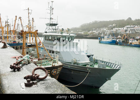 Le bateau patrouilleur des pêches, Saint Piran, dans le premier plan avec les bateaux de pêche et la ville de Newlyn en arrière-plan. Banque D'Images