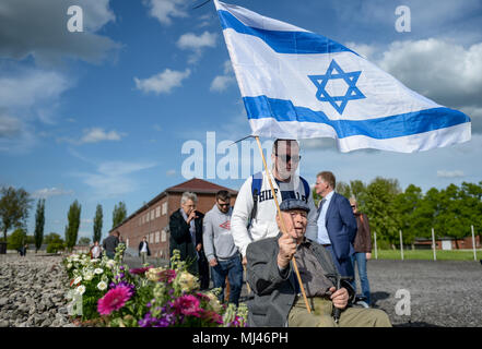 Déposée - 03 mai 2018, l'Allemagne, Hambourg : Un survivant de camp de concentration de Neuengamme est assis dans un fauteuil roulant tenant le drapeau israélien dans ses mains alors qu'il est poussé à travers les lieux avant la cérémonie de commémoration pour le 73ème anniversaire de la libération du camp de concentration de Neuengamme. Photo : Axel Heimken/dpa Banque D'Images