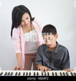 Garçon avec le professeur de musique ayant cours à Piano Banque D'Images