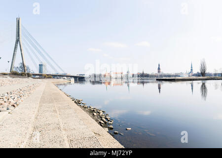 Cityscape in Riga, Lettonie. Vue de la rive de la rivière dans la ville faite pour la marche, à côté de l'immeuble de bureaux. Le centre-ville et le pont en arrière-plan Banque D'Images