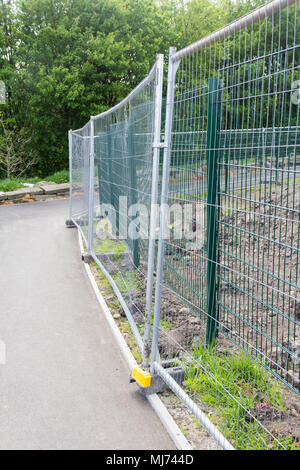 Une clôture de grillage métallique temporaire séparant un sentier fait surface à partir d'un site de construction. Banque D'Images