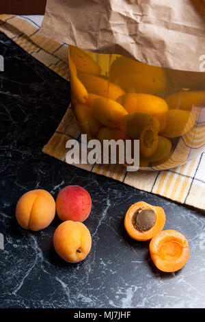 Les abricots bio mûres récoltées à l'heure d'été et grand bocal en verre avec compote d'abricot sucré en conserve sur marbre foncé. Composition dans un style rustique - orgue Banque D'Images