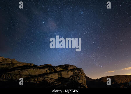 Nuit sur les Alpes sous ciel étoilé et les majestueuses falaises rocheuses sur les Alpes italiennes, avec la constellation d'Orion à l'horizon. Banque D'Images