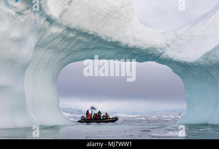 Cierva Cove, l'Antarctique - le 23 décembre 2016 : un zodiac plein d'vue à travers une arche dans un grand iceberg bleu Banque D'Images