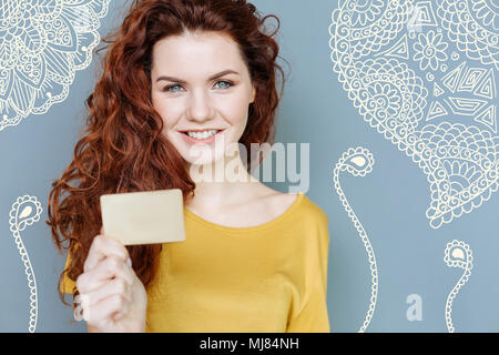 Smiling young woman standing avec une carte de crédit et à la satisfait Banque D'Images