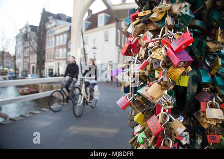 Close up d'un grand nombre de cadenas d'amour, deux personnes à bicyclette Équitation le long pont au canal en ville. Banque D'Images