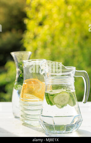 Trois variantes de limonade maison au citron, concombre et menthe. Dans pichets et limonade carafe sur jardin. Banque D'Images