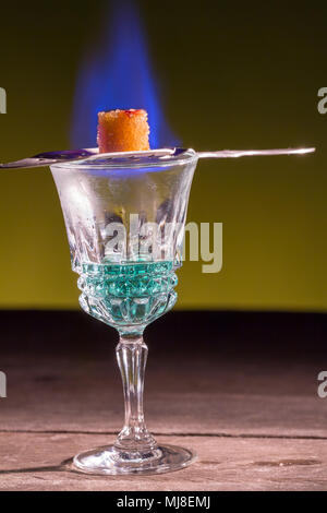 Sucre brûlant sur spoon en verre d'absinthe. Banque D'Images