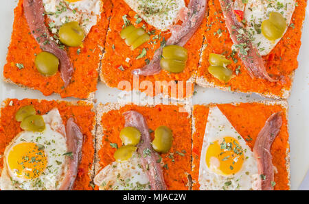 Tapas espagnol composé d'oeuf de caille frit, anchois, olive, poivre et origan Banque D'Images