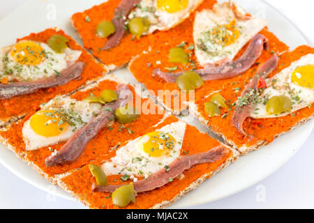 Tapas espagnol composé d'oeuf de caille frit, anchois, olive, poivre et origan Banque D'Images