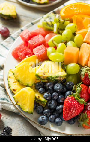 Plateau de fruits biologiques crus aux fruits rouges melons et raisins Banque D'Images