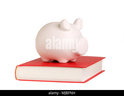 Une tirelire debout sur un livre fermé avec couvercle rouge symbolise le fait que la connaissance est récompensé, isolé sur fond blanc. Banque D'Images