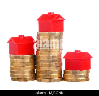 Petite maison rouge en haut des piles de pièces isolé sur fond blanc. Banque D'Images