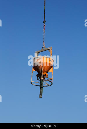 Libre de wagons-trémies suspendues à une grue de construction de gratte contre un ciel bleu. Banque D'Images