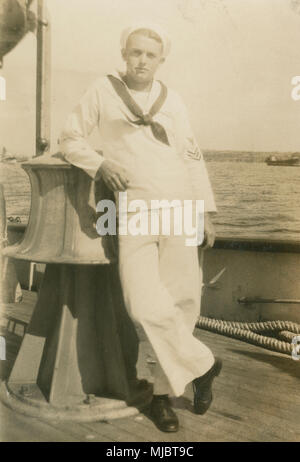 Meubles anciens c1922 photo, vue à bord du navire câble USCG Pequot. Un marin de la Garde côtière américaine dans un uniforme blanc robe, se penchant sur ce qui semble être le grand cabestan électrique sur le pont. SOURCE : tirage photographique original. Banque D'Images