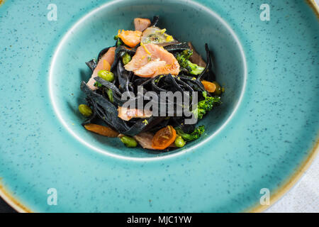 Spaghetti noir de l'Encre de Seiche avec le saumon et les légumes Banque D'Images