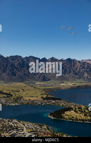 Vue aérienne de parapentes en ordre décroissant sur trois de Queenstown en Nouvelle-Zélande avec le lac Wakatipu sous un ciel bleu Banque D'Images