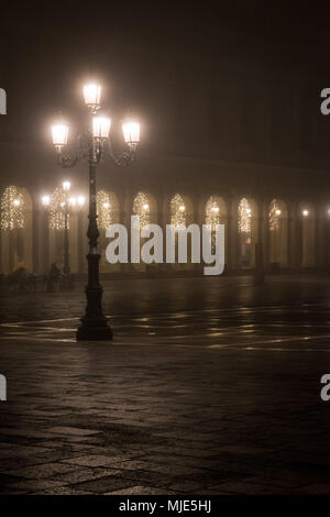 La Place St Marc / Piazza San Marco à Venise le soir pendant la période de Noël, un éclairage d'ambiance dans les arcades, presque déserte Banque D'Images