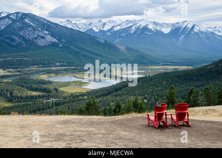 Deux chaises rouges sur une pente de montagne invitent à s'asseoir et profiter de la belle vue sur une vallée verdoyante à proximité de la ville de Banff, Canada Banque D'Images