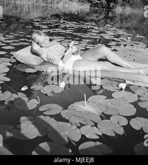 Eine junge Frau auf einer Luftmatratze auf einem Voir in der Wachau in Österreich, Deutschland 1930 er Jahre. Une jeune femme sur un matelas d'air sur un lac dans la région de Wachau en Autriche, l'Allemagne des années 1930. Banque D'Images