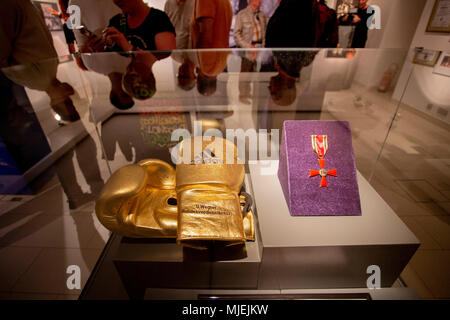 04 mai 2018, l'Allemagne, Gera : gants de boxe d'or et la Croix fédérale du mérite pour Ulli Wegner lors de l'exposition 'Ring gratuitement ! Ulli Wegner - Boxer, formateur, citoyen d'honneur" dans le musée de la ville de Gera. L'exposition spéciale est montrant les trophées et la carrière de Ulli Wagner du 04 mai 2018 au 28 avril 2019. Photo : Christoph Soeder/dpa Banque D'Images