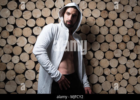 Portrait d'un jeune homme en bonne forme physique montrant son corps bien formé in Hoodie - Remise en forme musculaire Bodybuilder Athletic Model Posing Après Exercices sur Banque D'Images