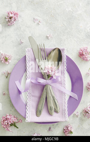 Décoration de table de printemps avec des fleurs lilas. Table élégante avec des fleurs lilas mauve, serviette et argenterie vintage sur fond rustique. Banque D'Images