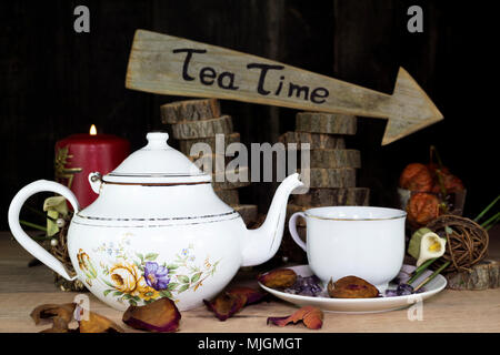 Tasse de thé et une théière sur la table en bois. Panneau de flèche avec du texte, l'heure du thé écrit dessus en l'arrière-plan Banque D'Images