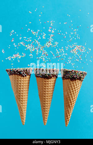 Ice cream cones avec sprinkles multicolores sur fond bleu. Banque D'Images