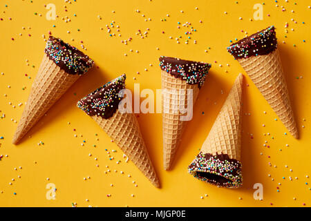 Cornet de crème glacée avec des paillettes colorées sur fond jaune. Banque D'Images