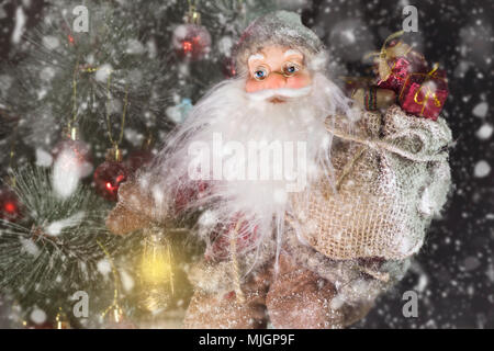 Le Père Noël en plein air à côté d'arbre de Noël dans la neige transportant des cadeaux aux enfants. Joyeux Noël & Nouvel An concept Banque D'Images