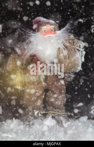 Le Père Noël en plein air à côté d'arbre de Noël dans la neige transportant des cadeaux aux enfants. Joyeux Noël & Nouvel An concept Banque D'Images