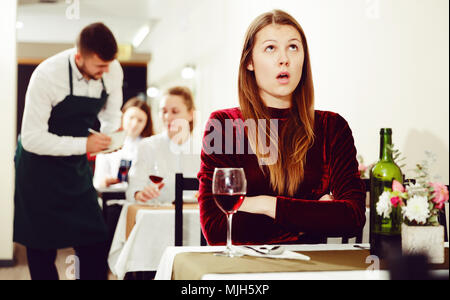 Femme élégante en colère s'attend à ce que l'homme pour le dîner dans le restaurant de luxe intérieur. Banque D'Images