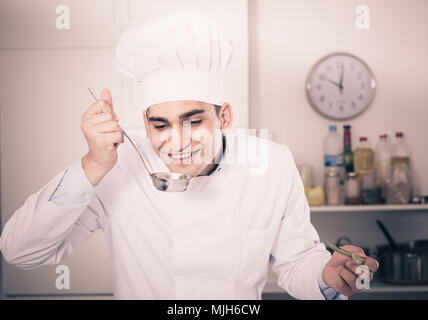 Jeune homme degustating soupe sur cuisine. Banque D'Images