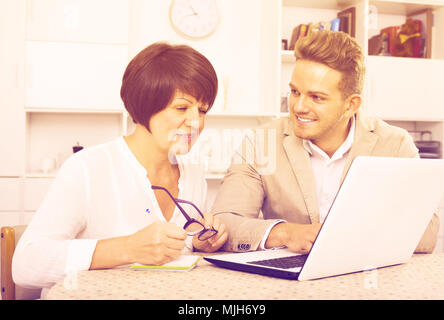 Smiling maman et fils d'examiner de nouveaux logiciels sur laptop sitting at table Banque D'Images