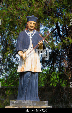 Sculpture d'un homme d'une croix en arrière-cour de l'église catholique Banque D'Images