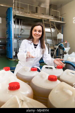 Hot girl les bouteilles en plastique de remplissage avec de l'huile d'olive dans un appareil industriel Banque D'Images