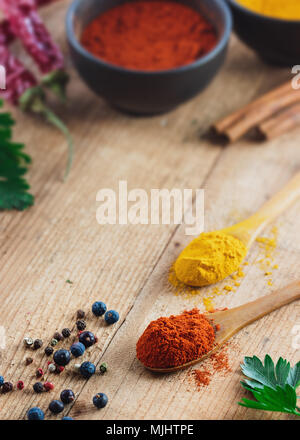 Cuillère en bois remplis de paprika sur table en bois rustique. Différents ingrédients sur la table. Banque D'Images