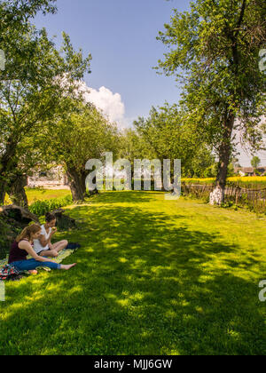 Zalipie, Pologne - 20 mai 2017 : Deux jeunes fille sont assis dans le coin de jardin entouré de saules pleureurs Banque D'Images