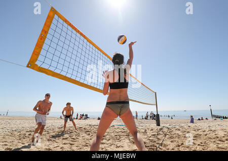 Les gens prennent part à une partie de beach-volley sur la plage de Boscombe de Dorset, comme les amoureux du soleil sont mis à griller dans la vague de printemps, avec des vacances de banque lundi prévue est la plus chaude depuis le début des études. Banque D'Images