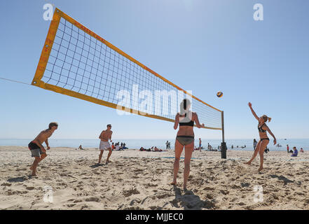 Les gens prennent part à une partie de beach-volley sur la plage de Boscombe de Dorset, comme les amoureux du soleil sont mis à griller dans la vague de printemps, avec des vacances de banque lundi prévue est la plus chaude depuis le début des études. Banque D'Images