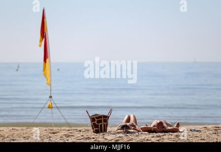 Les gens profiter du beau temps sur la plage de Boscombe de Dorset, comme les amoureux du soleil sont mis à griller dans la vague de printemps, avec des vacances de banque lundi prévue est la plus chaude depuis le début des études. Banque D'Images