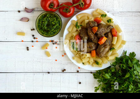 Des pâtes et de foie d'oie poêlé (poulet, canard) au pesto et tomate sur un fond blanc. La vue de dessus Banque D'Images