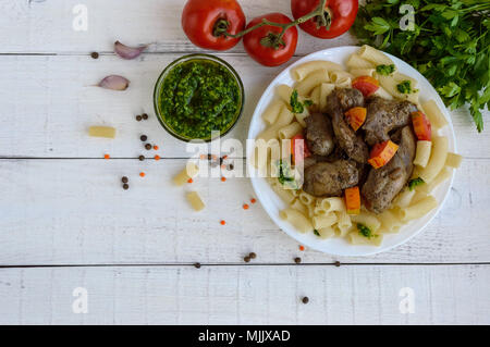 Des pâtes et de foie d'oie poêlé (poulet, canard) au pesto et tomate sur un fond blanc. La vue de dessus Banque D'Images