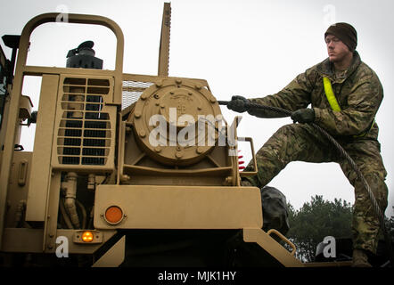 La CPS. Tyrel Denton, un chauffeur de camion militaire affecté à la 32e Compagnie de composite, 68e Bataillon de soutien de soutien au combat, 4e brigade de maintien en puissance, 4e Division d'infanterie, se déroule un câble sur un système de transport d'équipement lourd (HETS) sur commande pour remorquer un autre véhicule à un aérodrome près de Pozwidz, Pologne, 5 décembre 2017. Denton, un Rushville, Neb. native, et les autres soldats américains dans son unité font partie d'un déploiement de neuf mois en Pologne. (U.S. Photo de l'armée par la CPS. Andrew McNeil / 22e Détachement des affaires publiques mobiles) Banque D'Images