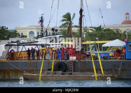 Les membres de l'Ouragan Maria FSE-10 Porto Rico unified command sauver un navire dans le port de San Juan, le 5 décembre 2017. Le commandement unifié est suppression de navires touchés par Maria, qui constituent actuellement la pollution et les menaces environnementales, sans frais ni pénalité pour les propriétaires. (U.S. Photo de la Garde côtière du Maître de 2e classe Lara Davis) Banque D'Images